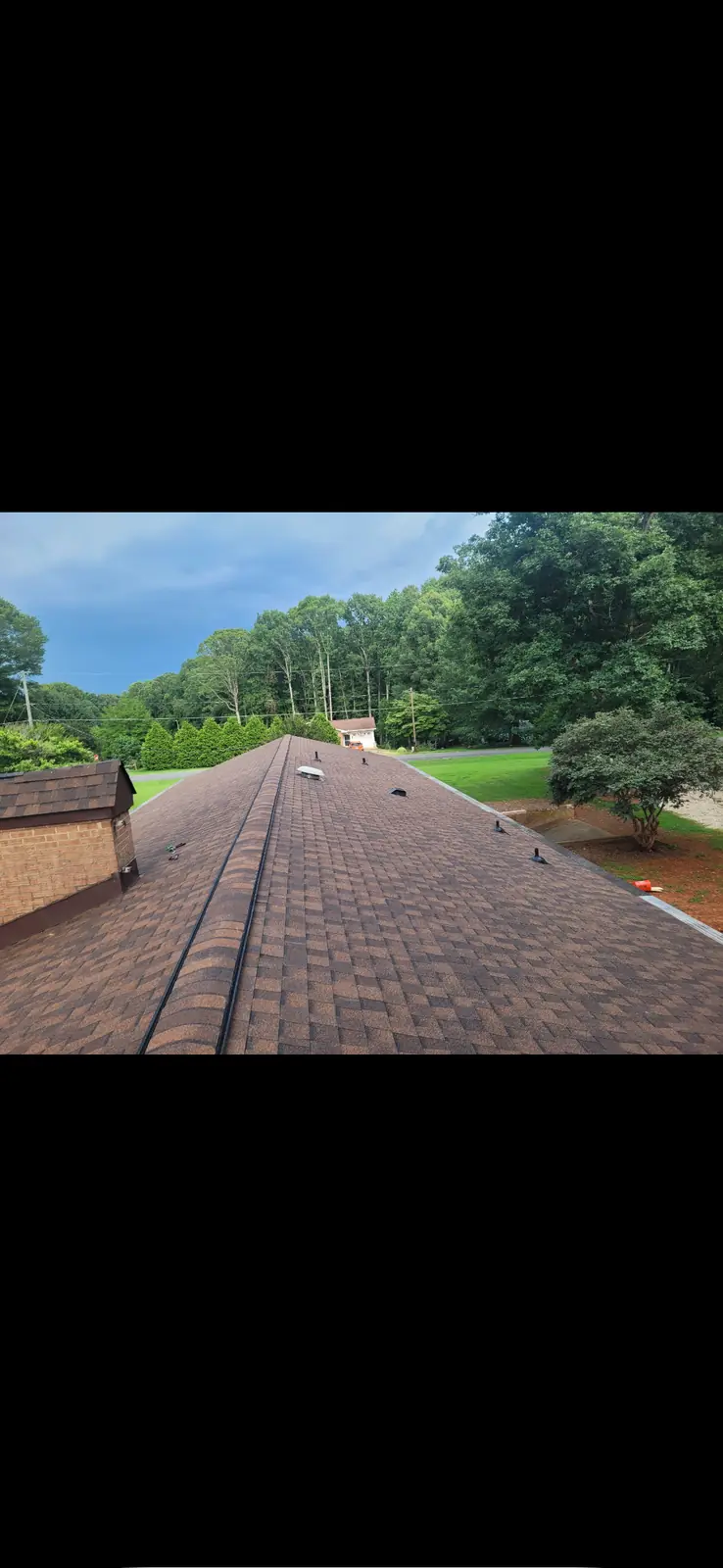 A completed brown shingle roof seen across the slope
