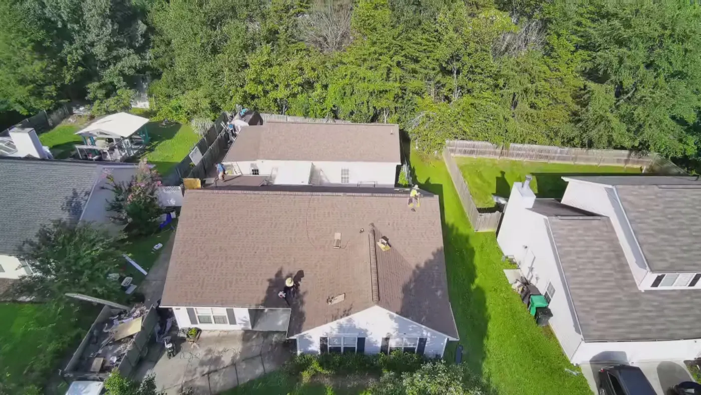 Drone view of the crew running shingle courses across a brown roof