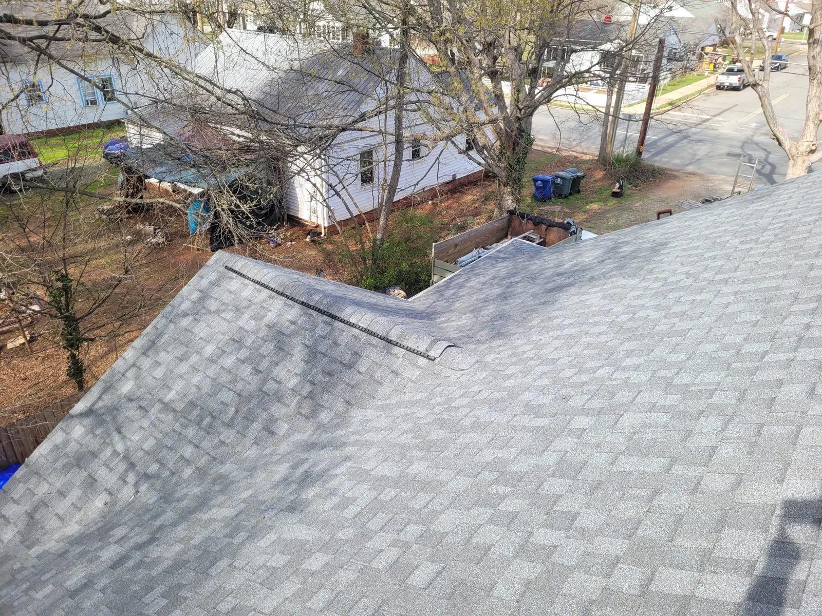 New pewter gray shingles and ridge vent on a steep roof in spring