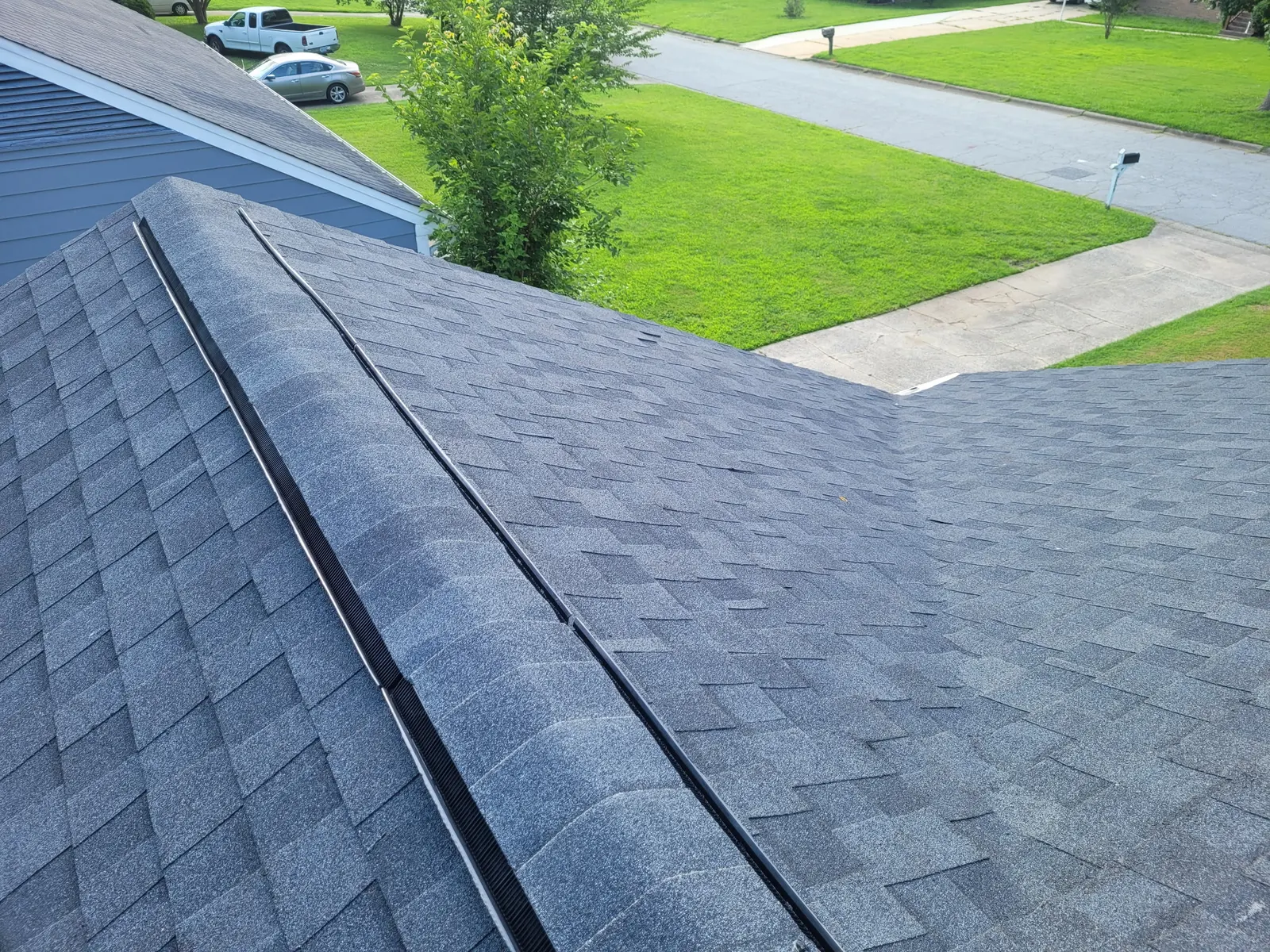 New ridge vent running the length of a navy shingle roof
