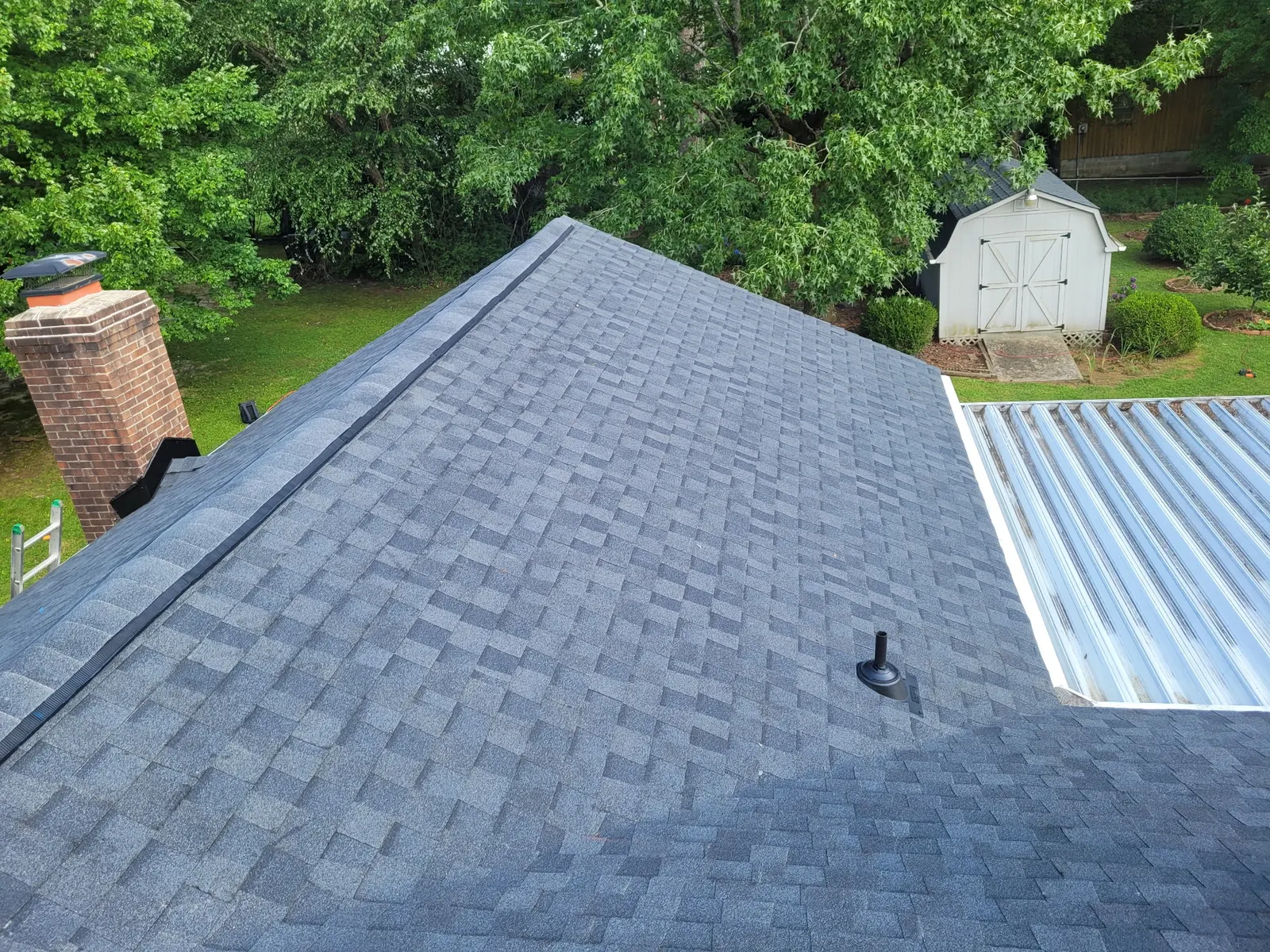Finished slate blue shingle roof with a brick chimney and fresh flashing