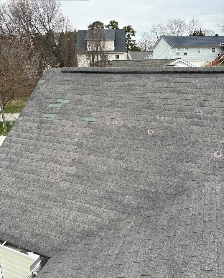 A gray shingle roof slope with small chalk circles marked across it