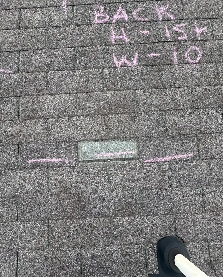 Chalk writing and a chalk line across gray asphalt shingles