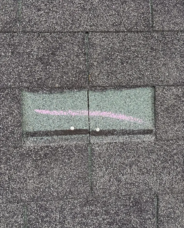 A chalk line drawn across a single shingle tab with two nail heads showing