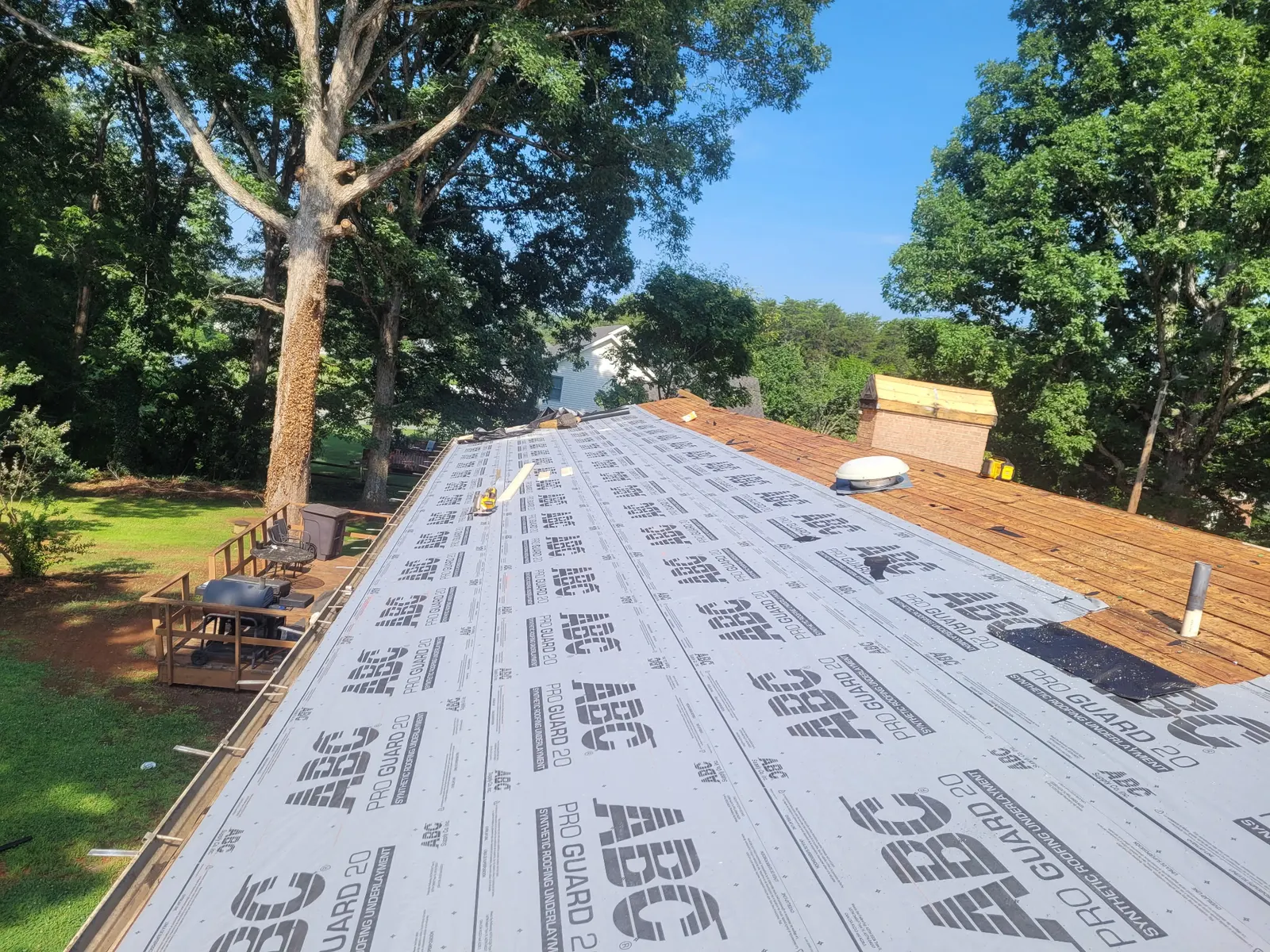 Synthetic underlayment rolled across the full roof, half covering the old decking